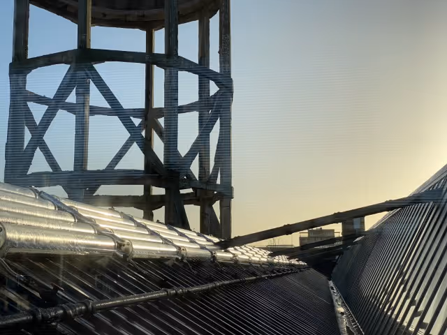 Rows of solar thermal collectors on pitched roof in industrial area. 