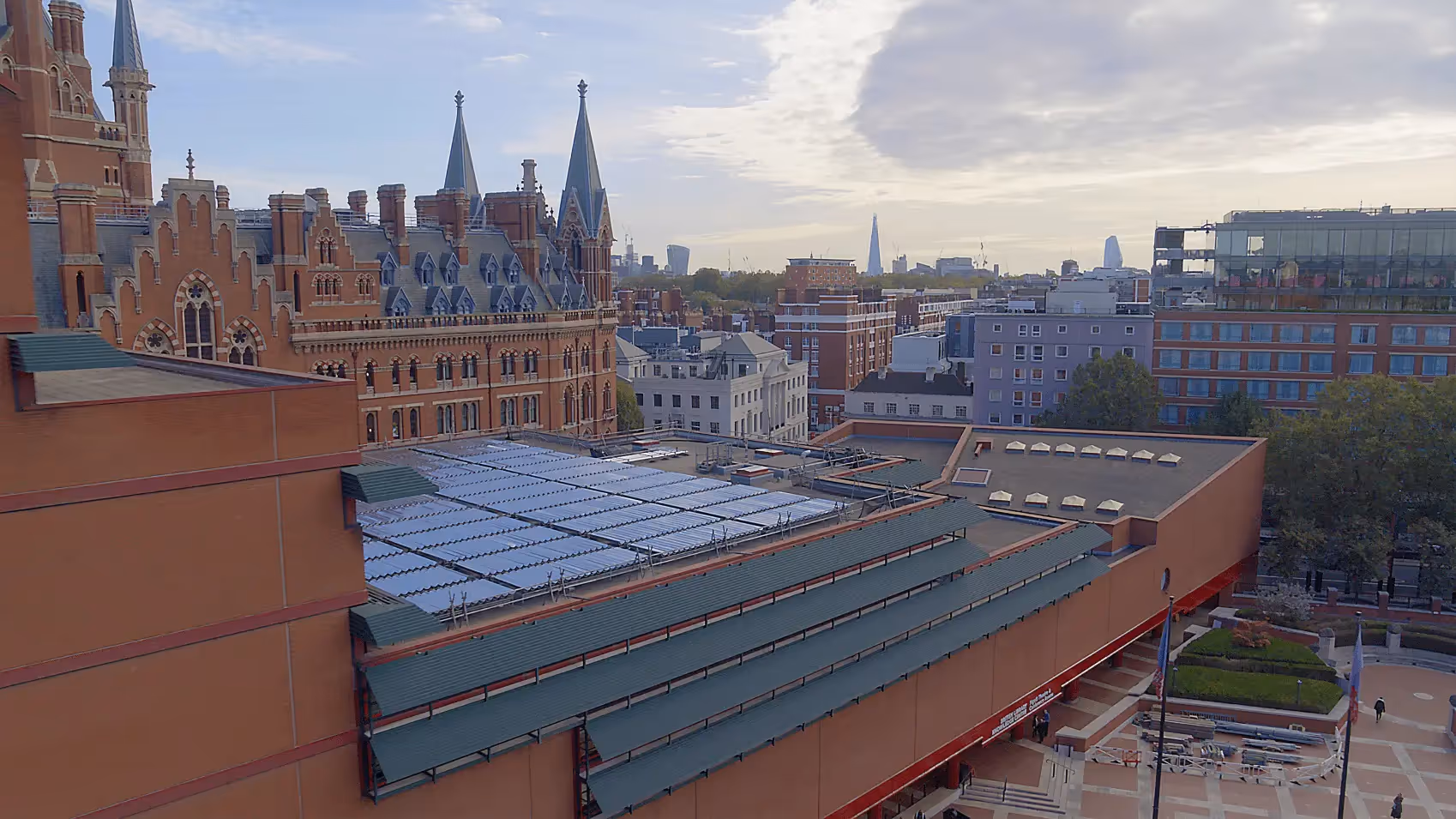 Drone shot of British Library with solar thermal collectors on roof and London skyline in background