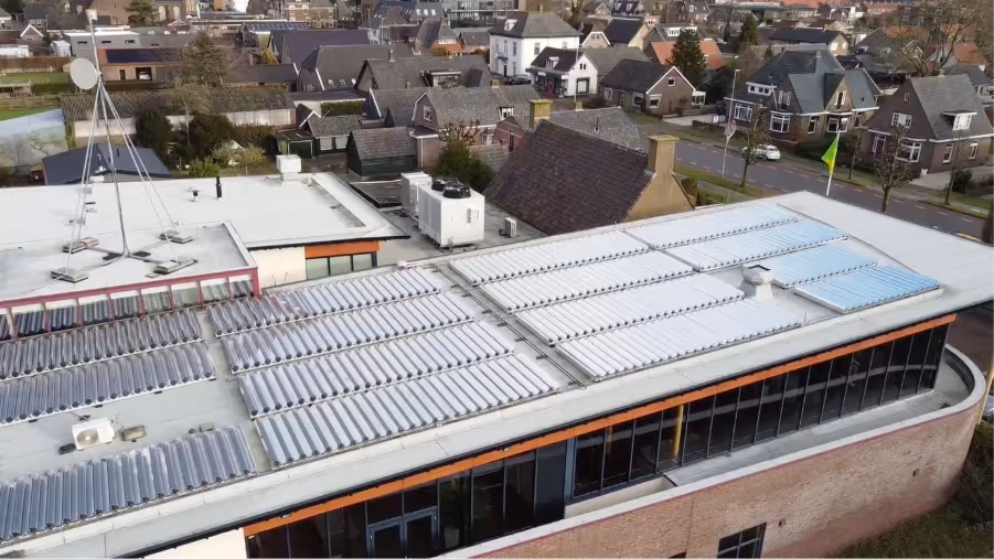 Solar thermal panels on a roof of a building with a few buildings around it