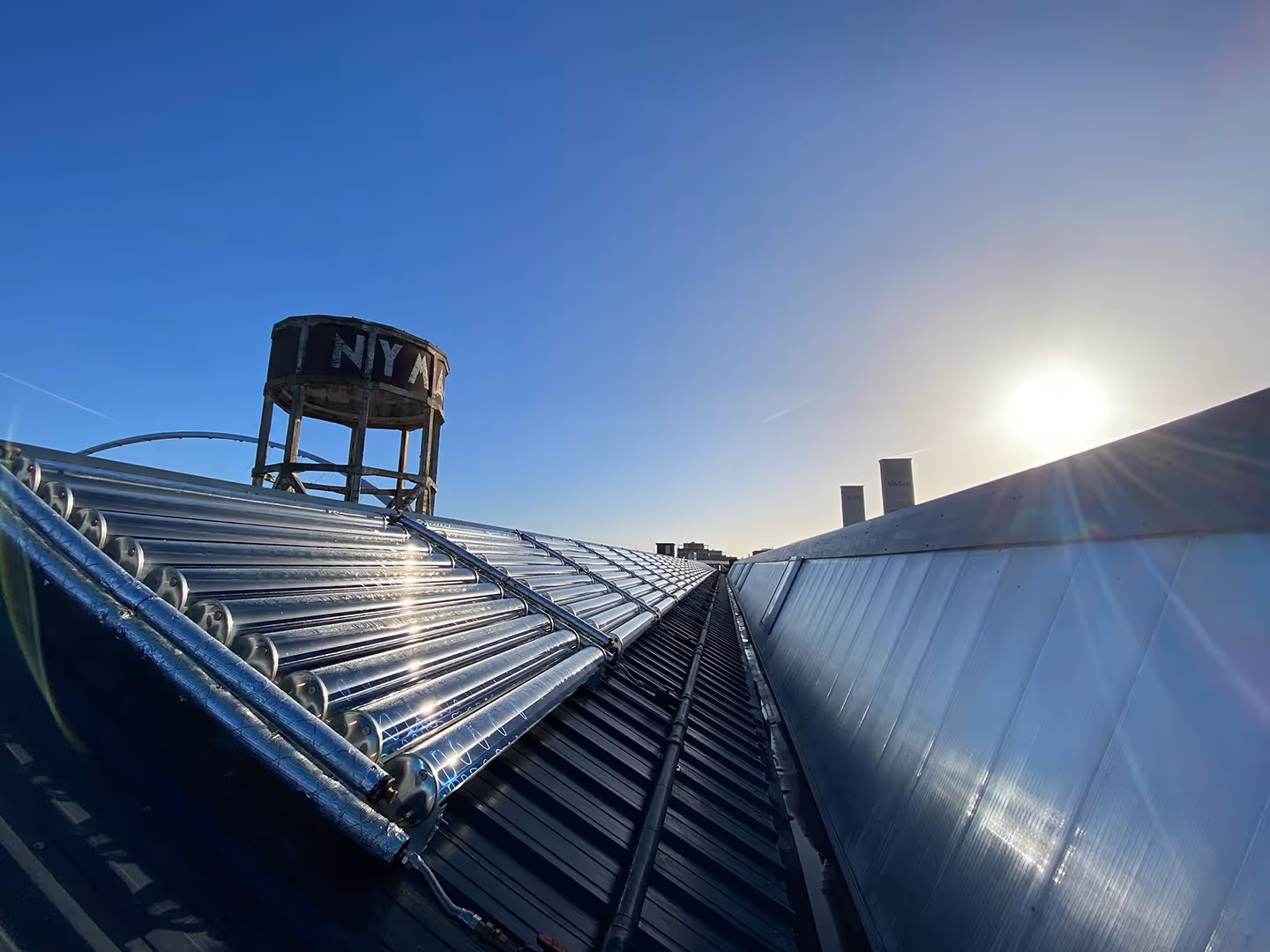 Solar thermal collectors on industrial pitched roof with reflecting sunlight