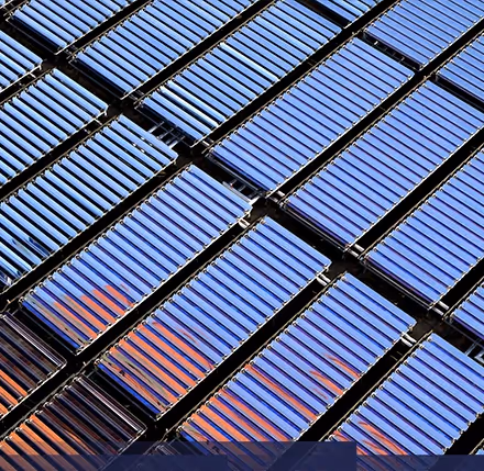 Rows of solar thermal collectors with sunlight reflection on flat roof.