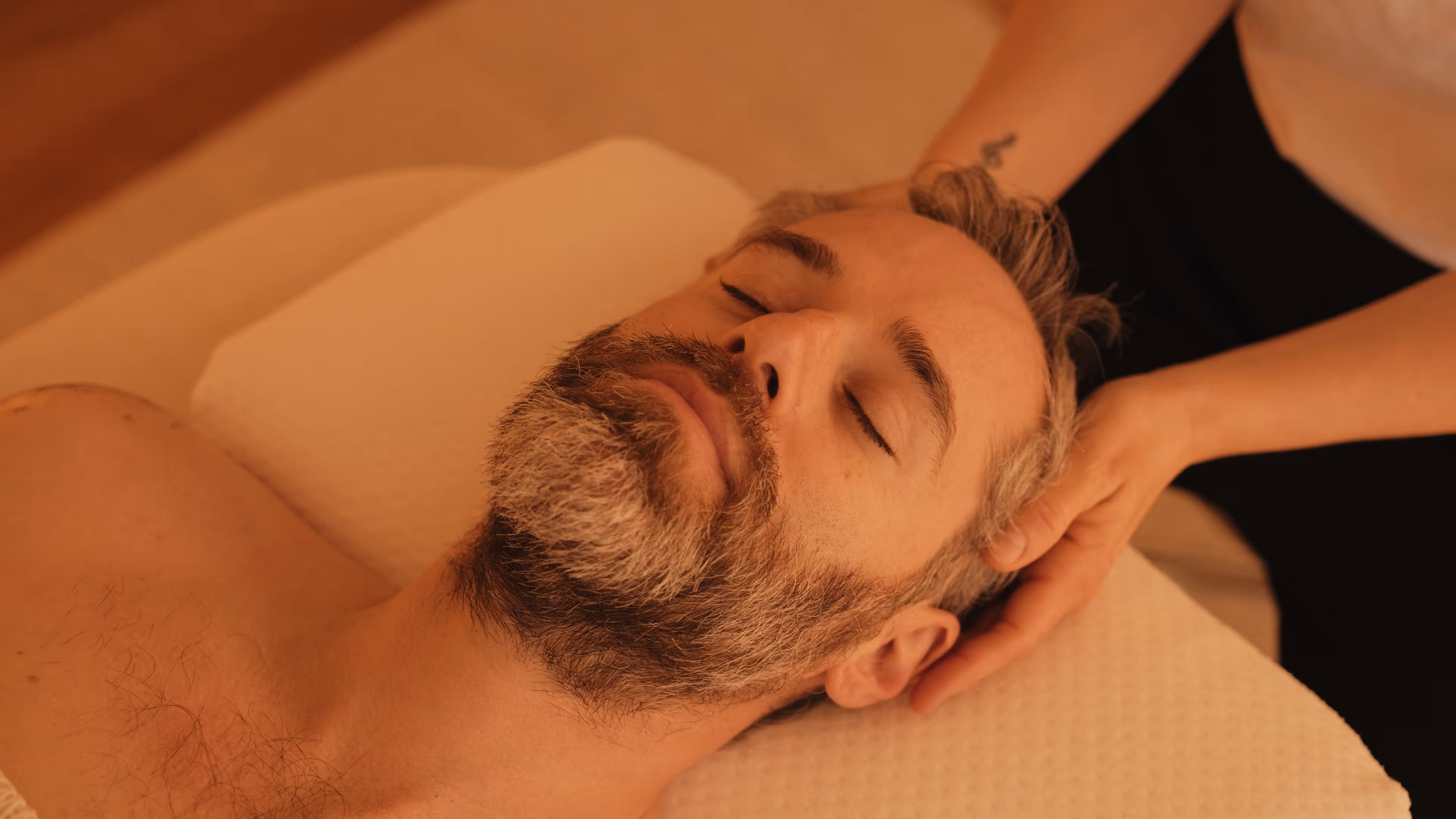 Ein Mann entspannt mit geschlossenen Augen während einer achtsamen Kopfmassage von Lisa