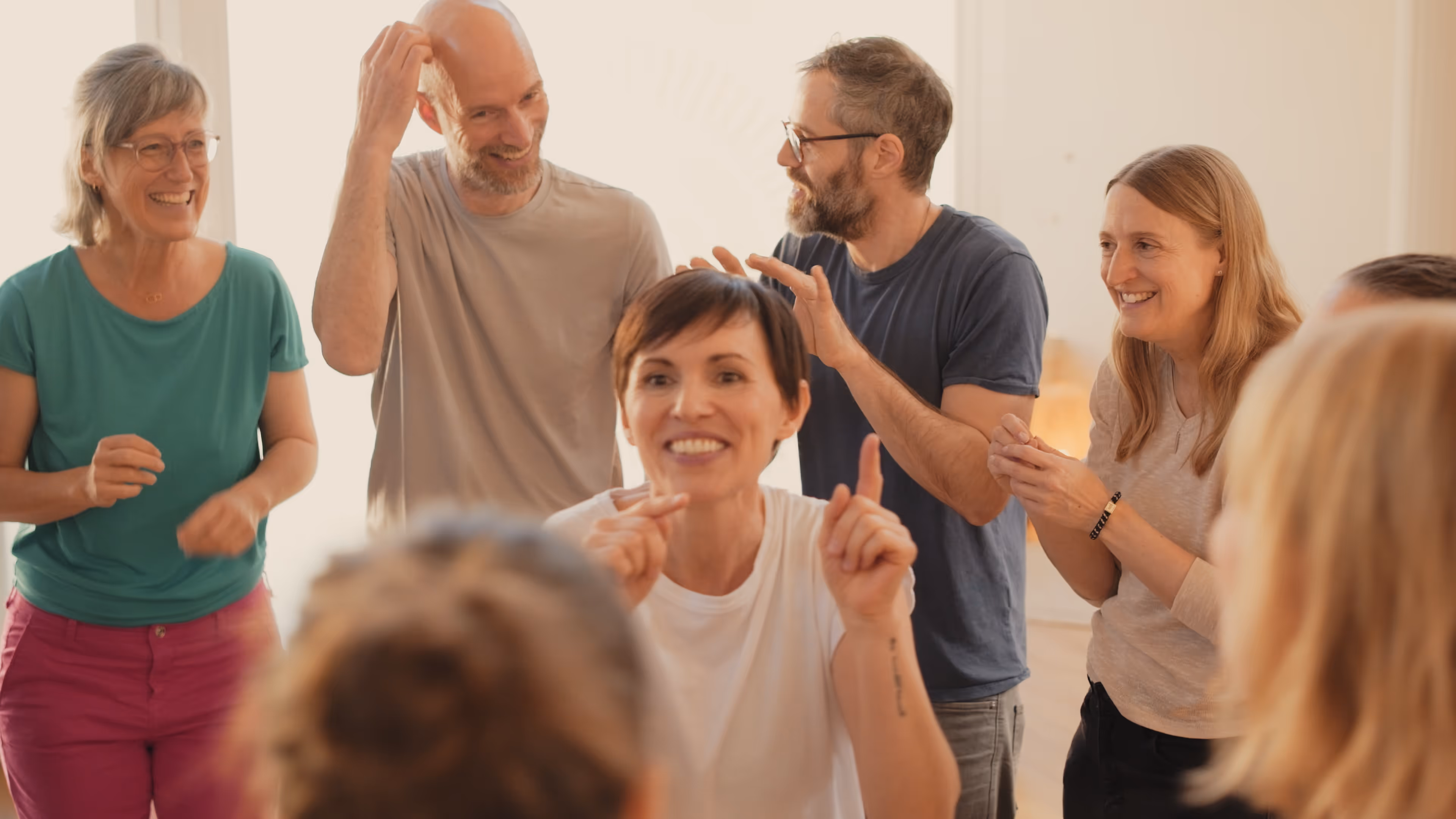 Gruppe von Erwachsenen, die lachen und in einem Raum interagieren.