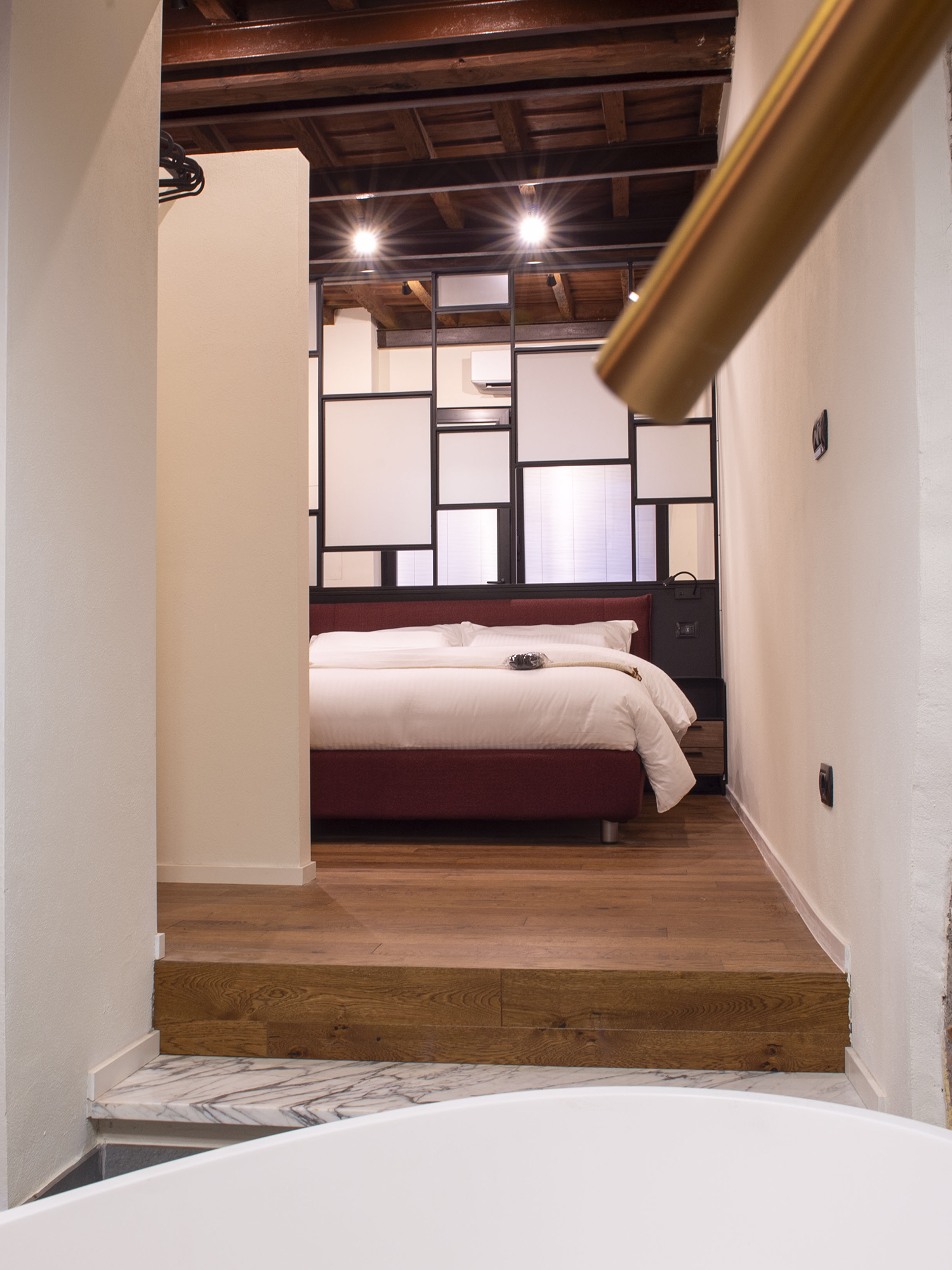 A bright dining room with a dark table, white chairs, a striped bench, a rug, and a gold chandelier