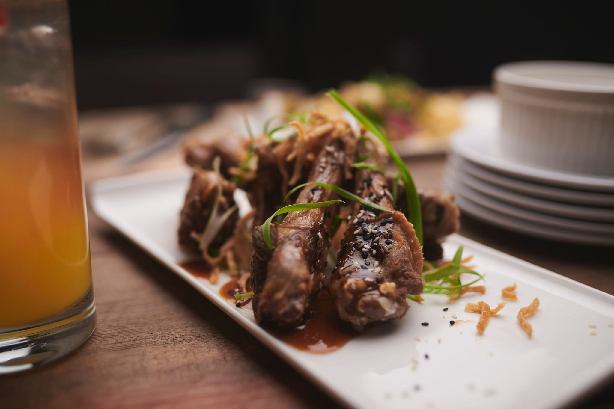An appetizer of duck drumettes on a white plate.
