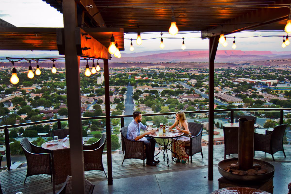 Couple dining on an outdoor patio overlooking St. George, Utah during sunset.