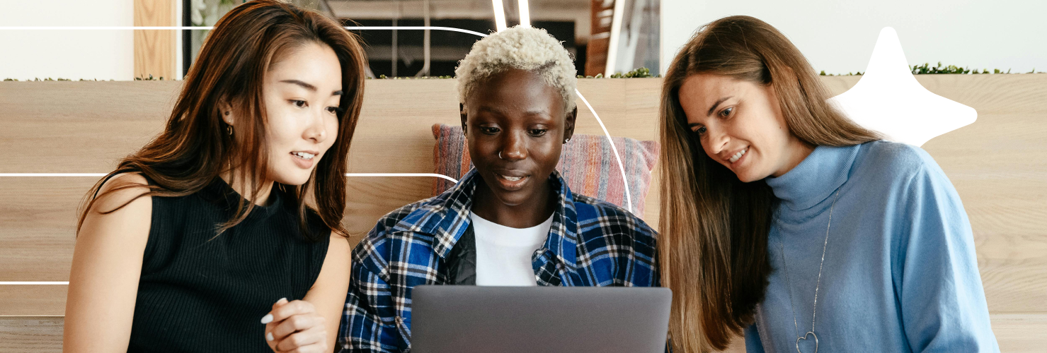 3 girls sat together looking at a laptop.