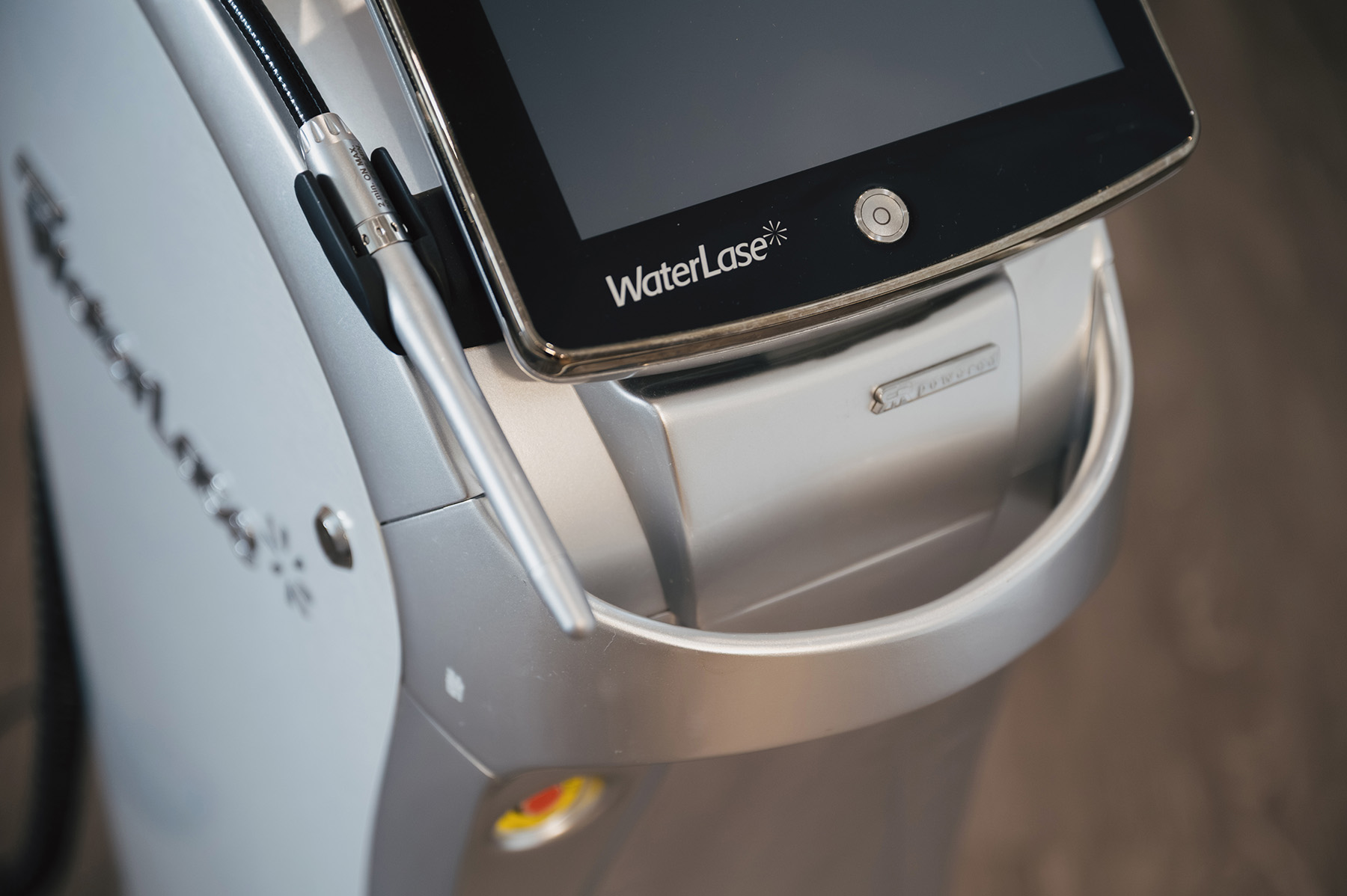Close-up of a WaterLase dental laser device with a touchscreen and handheld wand.