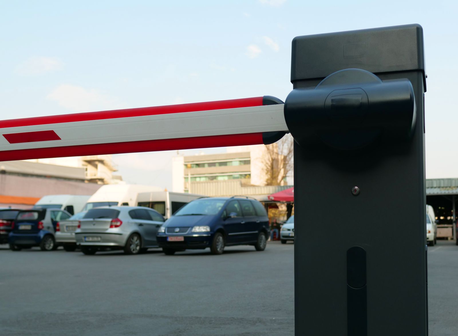 Barrera de acceso a estacionamiento con autos al fondo