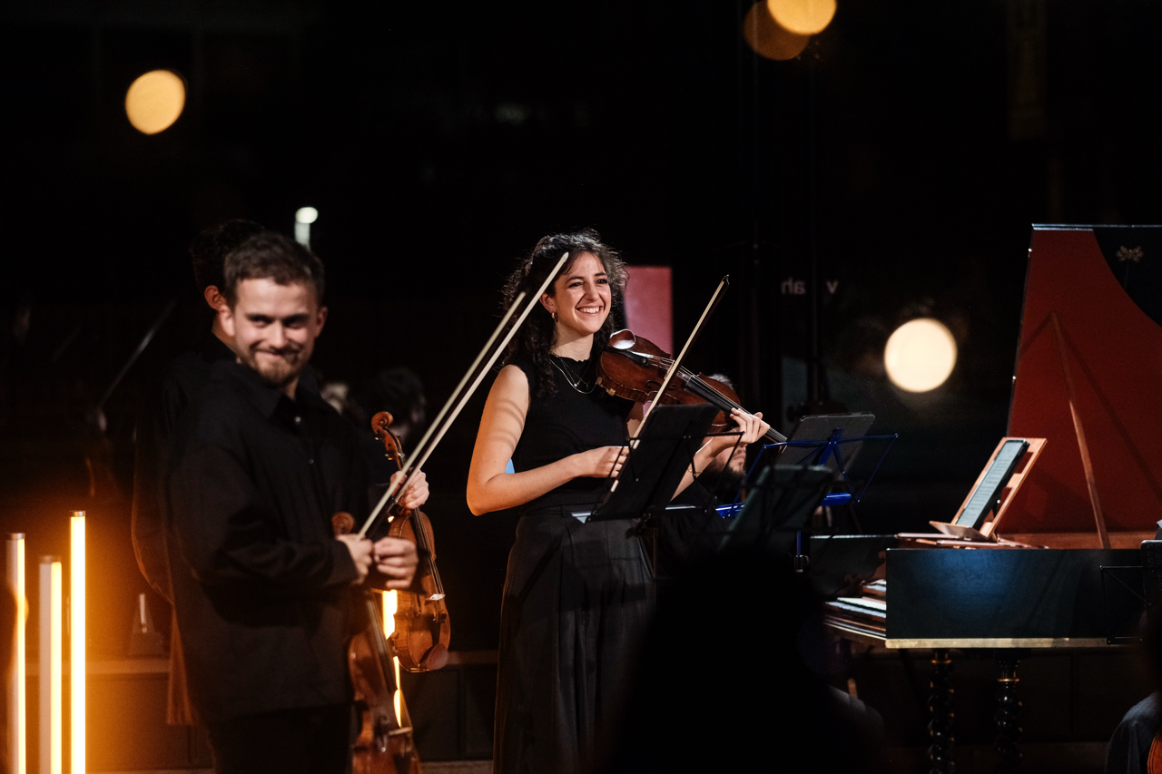 Ayla Sahin and Dmitry Smirnov smiling, during a performance with harpsichord.