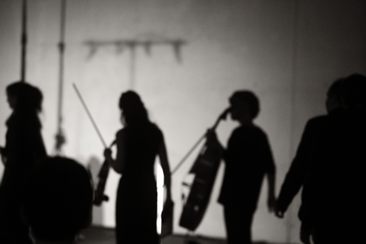 Shadows of the performers as they leave the stage, white lighting.