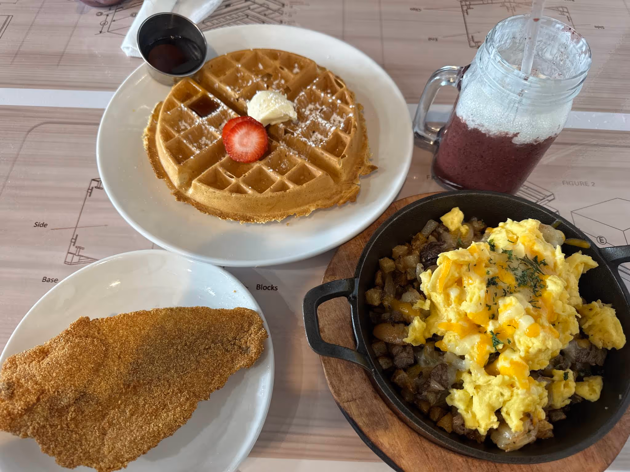 A plate of food with a waffle, fish, and eggs.