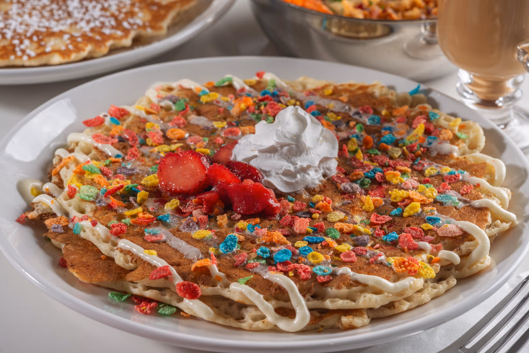 A plate of food with a strawberry and whipped cream on top.
