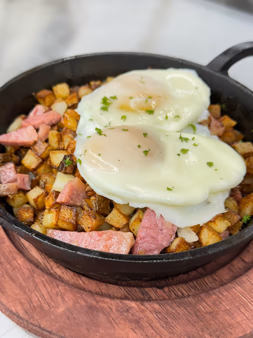A black bowl filled with eggs, potatoes, and ham.