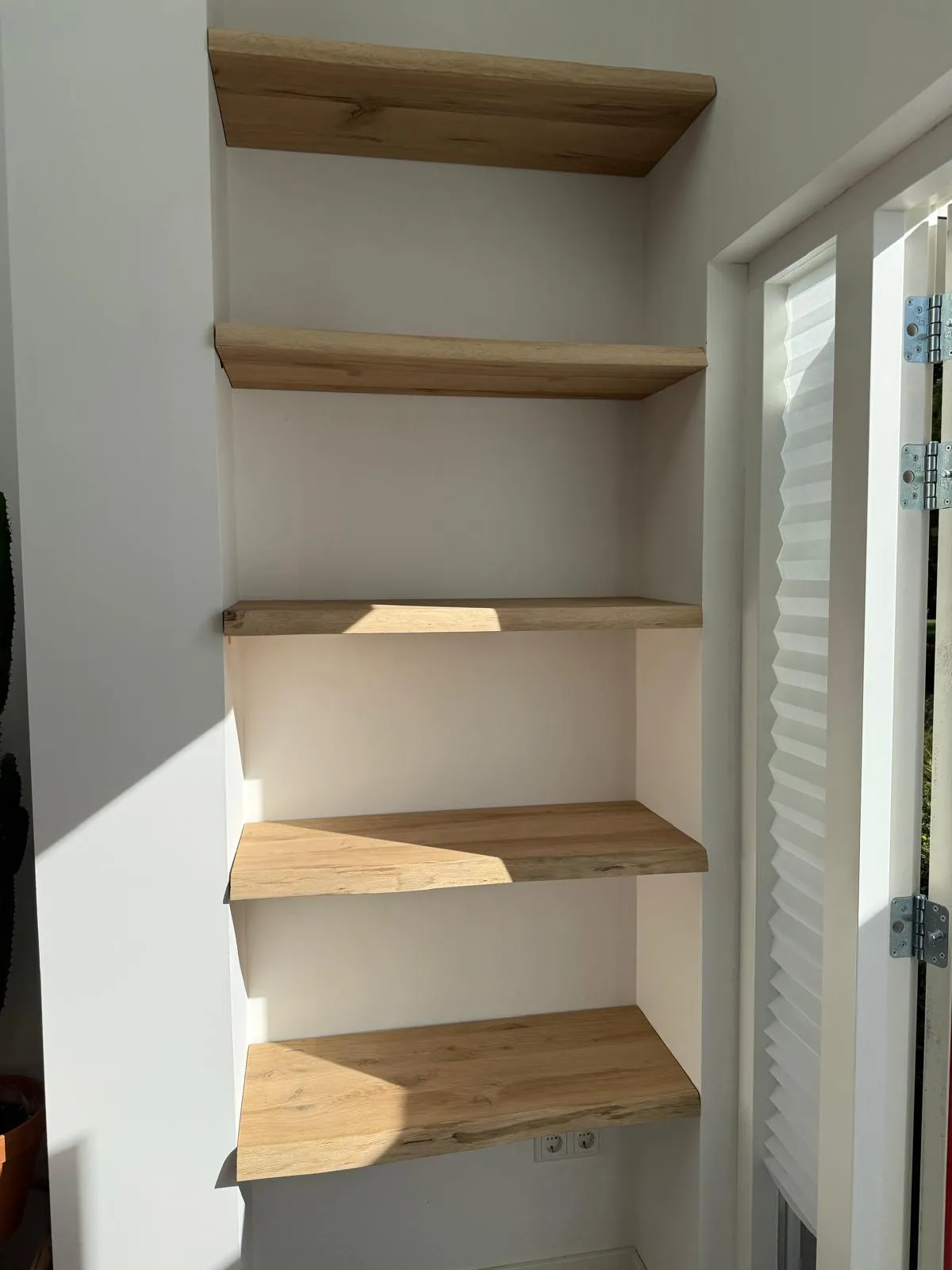 Op maat gemaakte planken in licht hout, geplaatst in muurnis