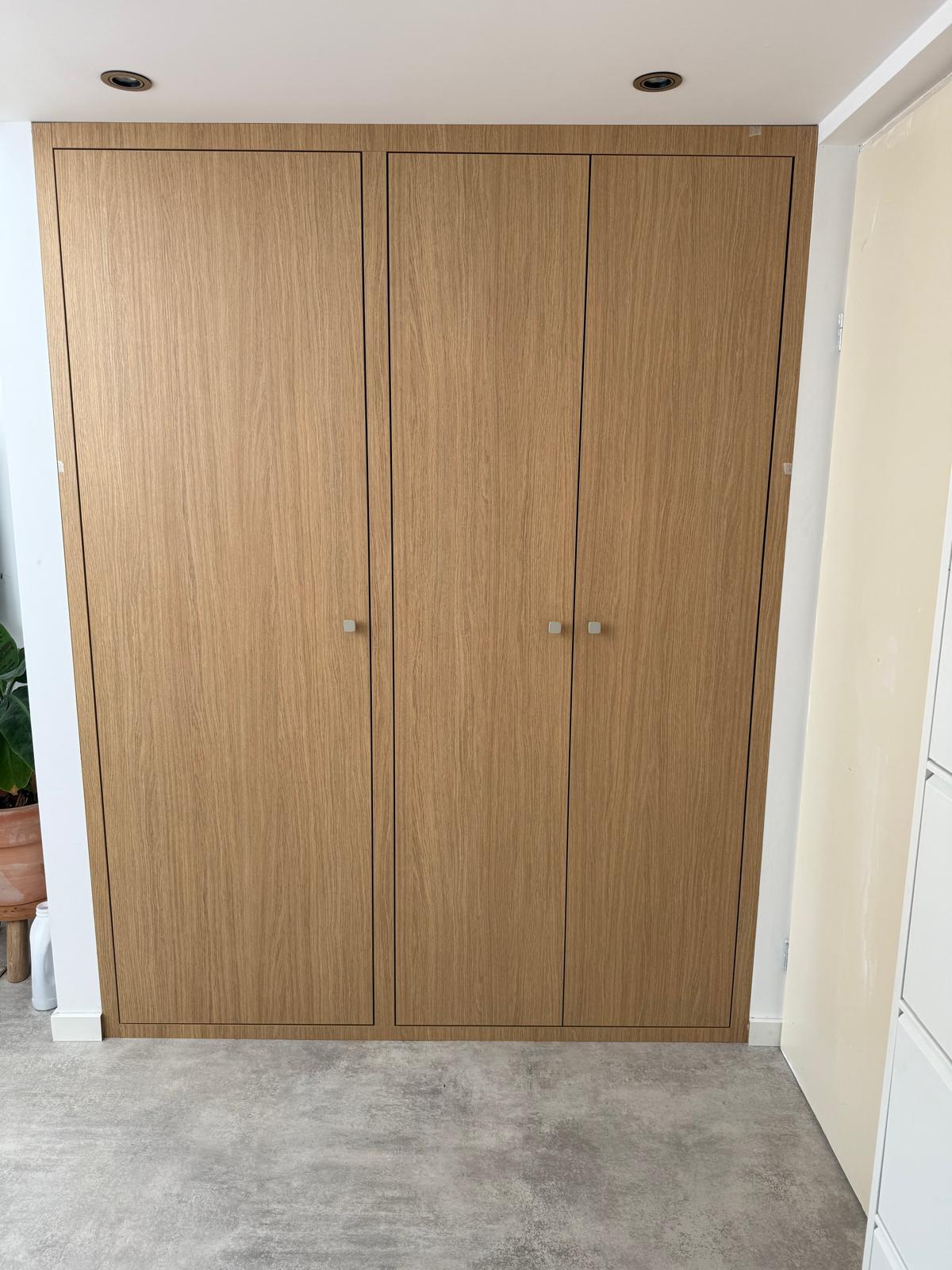 Gesloten wasmachinekast in lichte houtkleur met deuren