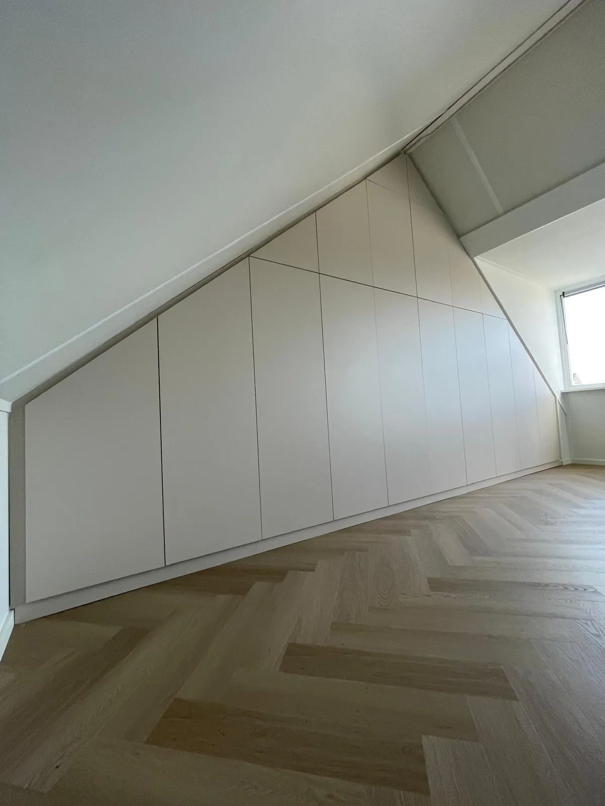 Grote schuine wandkast in beige over volledige muurbreedte