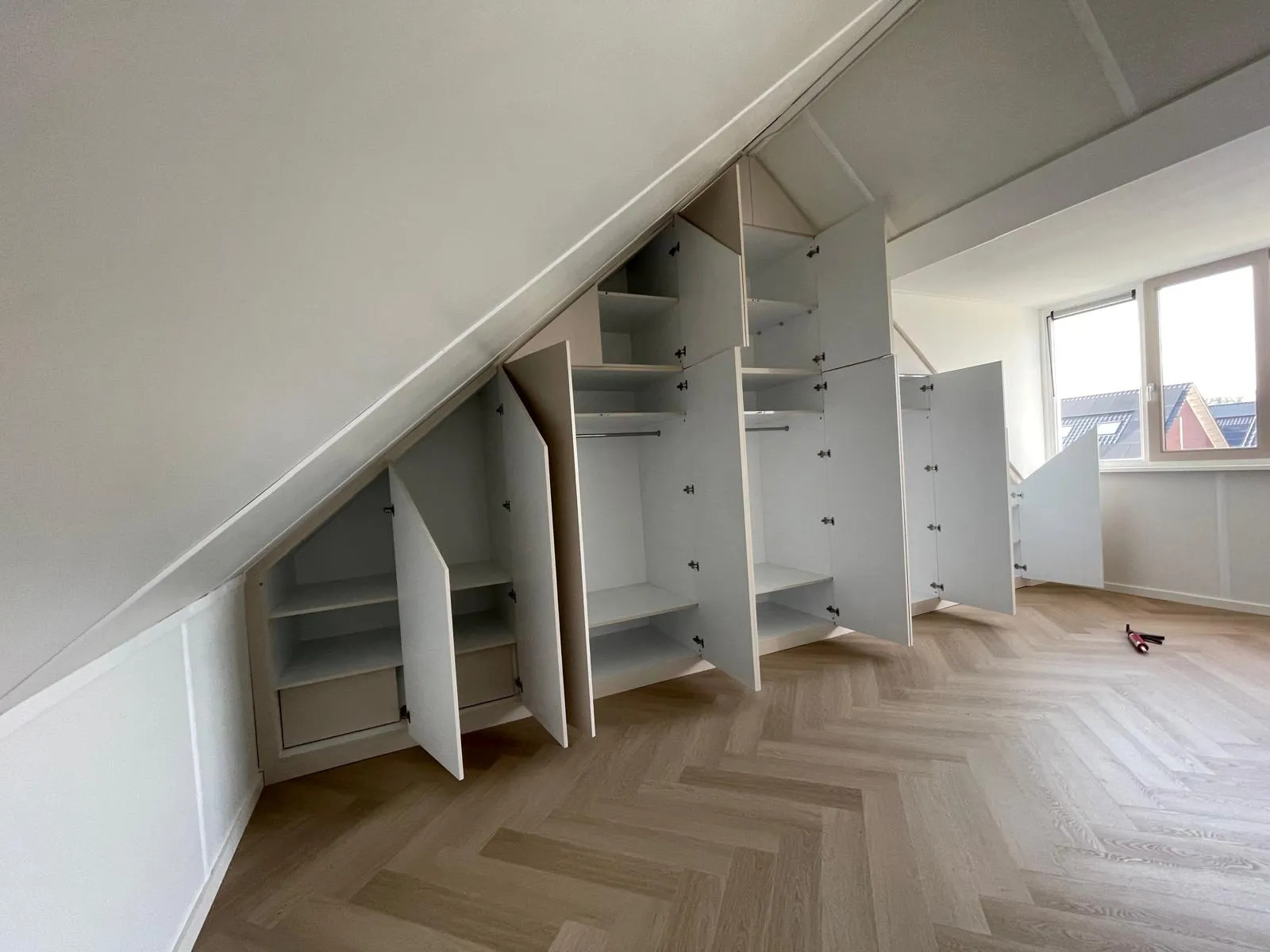 Geopende grote schuine wandkast in beige met zichtbare indeling