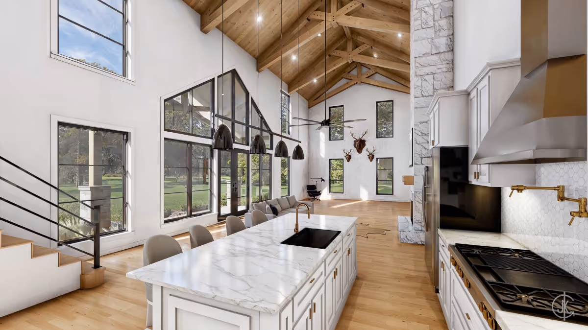 Modern farmhouse kitchen with vaulted ceiling, large windows, and marble island