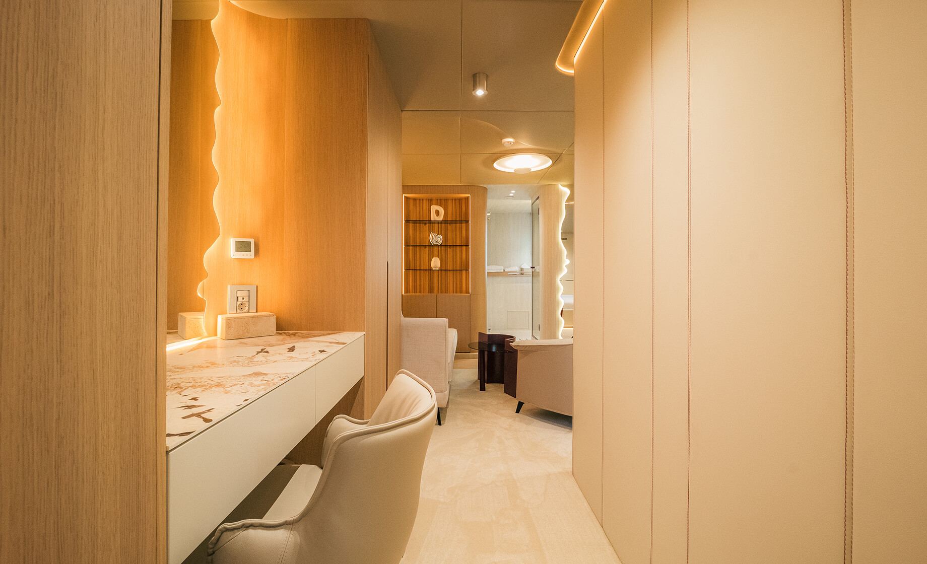 Elegant yacht interior hallway with a marble-top vanity desk, soft ambient lighting, and modern seating area.