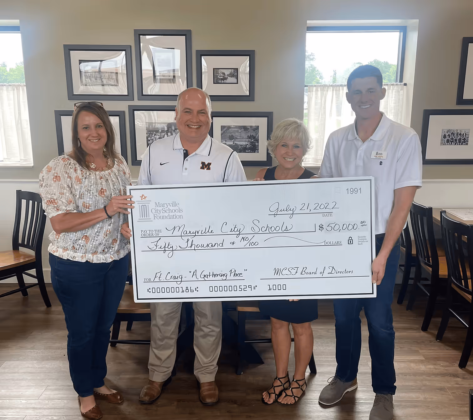 Four smiling adults standing indoors holding a large check for $50,000 made out to Maryville City Schools dated July 21, 2022.