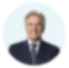 Blurred image of a person in a suit against a light blue background.