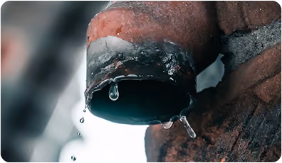 Close-up of a rusty pipe with water droplets dripping from its opening.