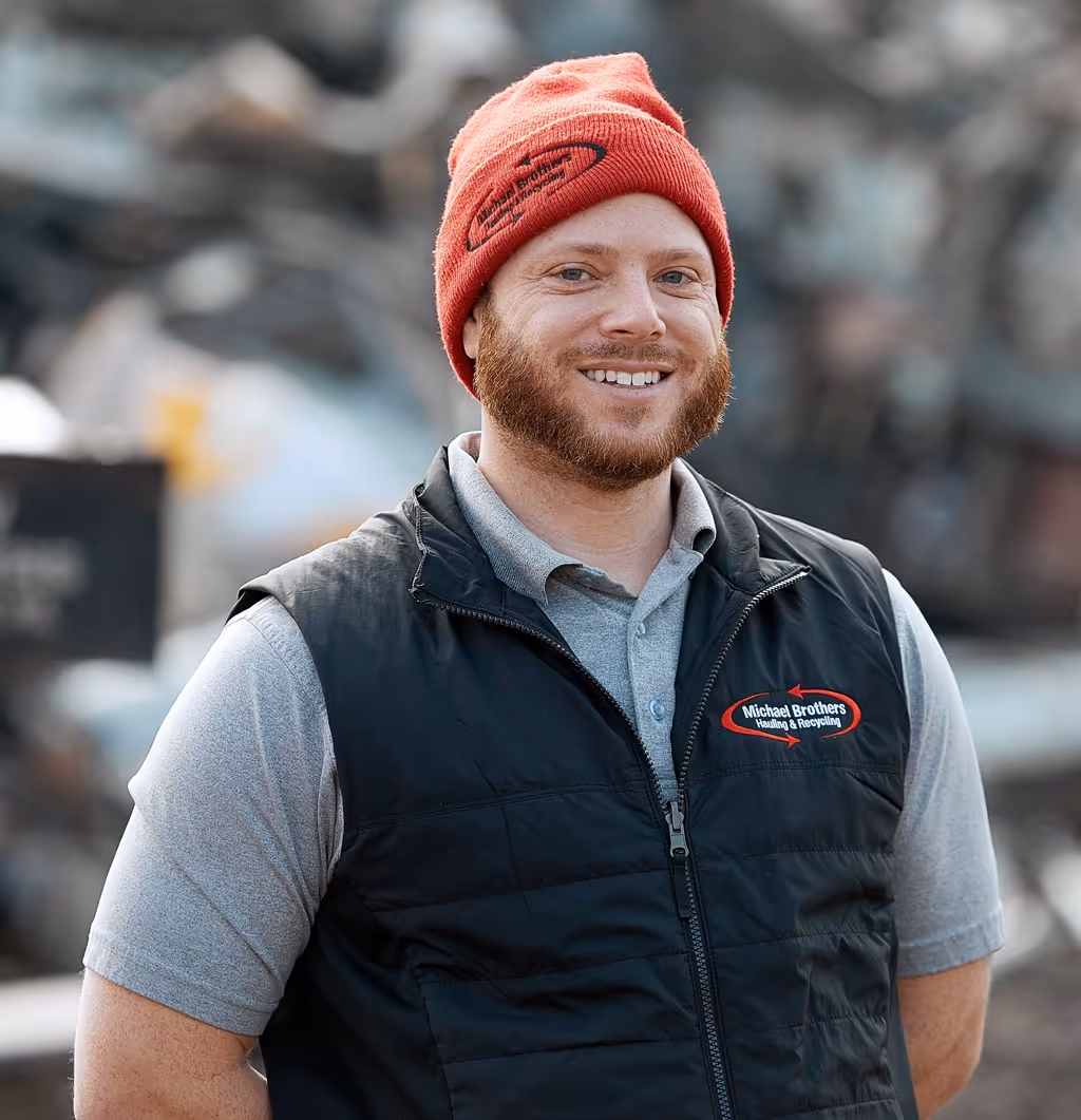 Rob wearing a red beanie and a black vest with Michael Brothers Hauling & Recycling logo.