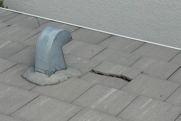Broken concrete tile next to goose neck vent on tile roof in Naples, FL
