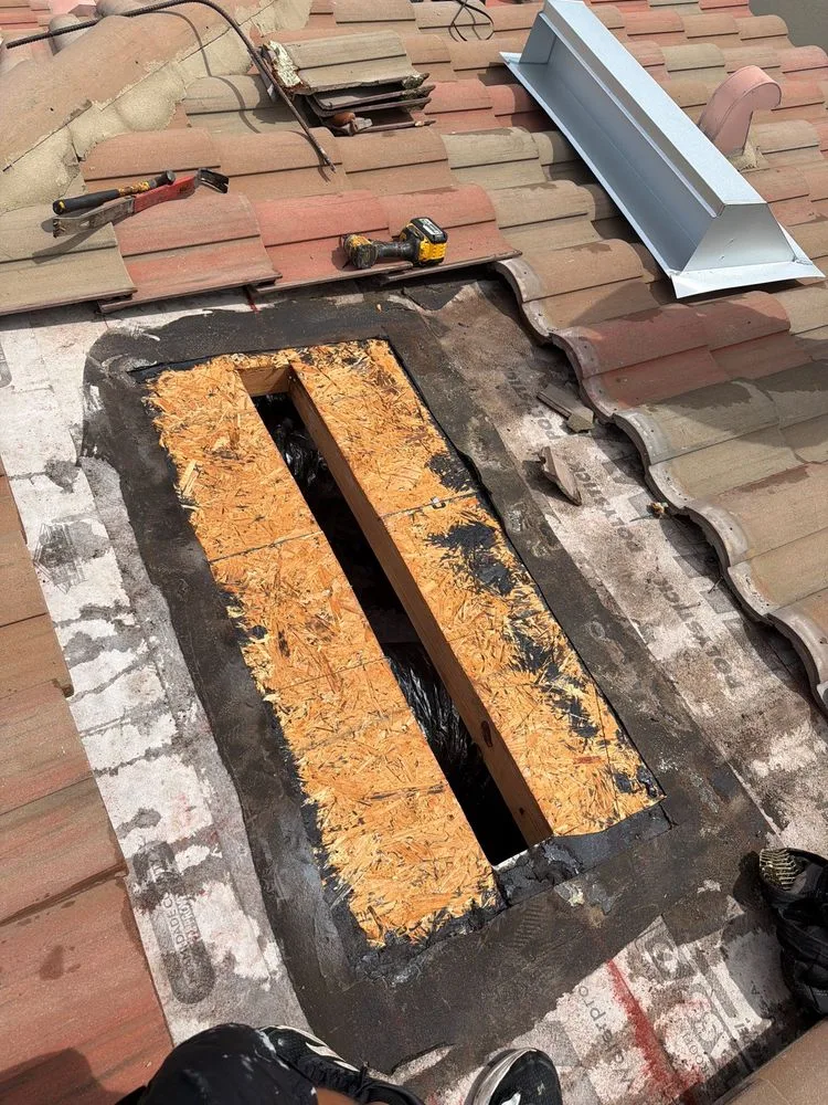 Tile roof in Naples opened up around a roof vent, with the old vent removed and the roof deck exposed