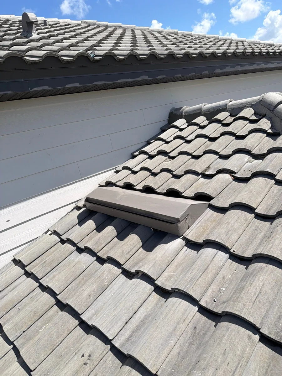 Finished roof-to-wall repair with gray roof tiles restored and the vent visible