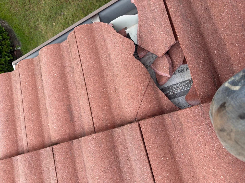 Broken red roof tiles exposing the area beneath the roof covering
