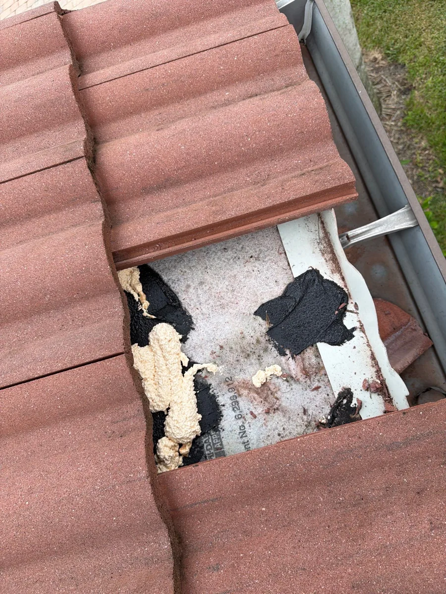 Lifted roof tile showing the exposed underlayment and attachment beneath