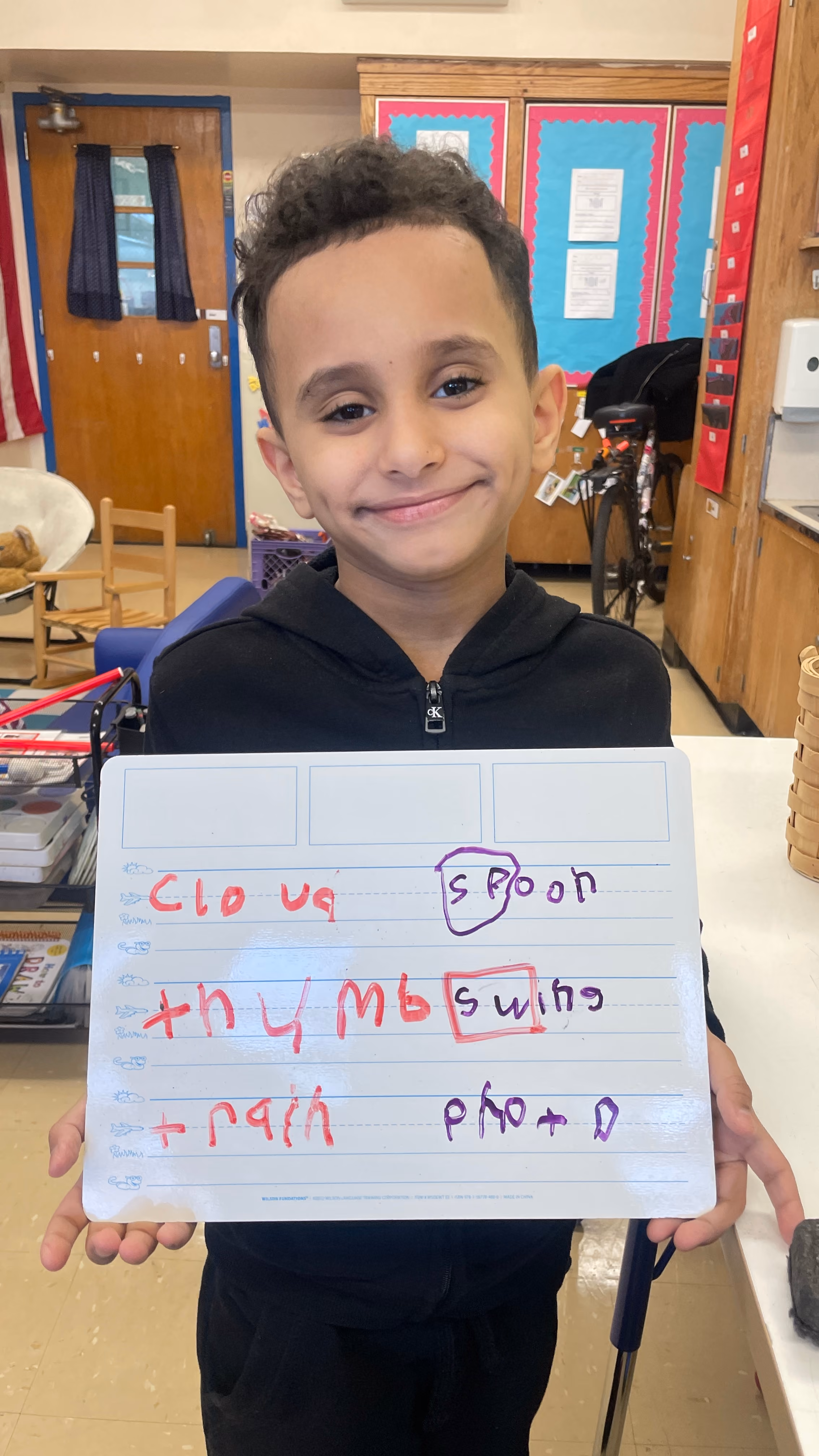 Student holding whiteboard with spelling words
