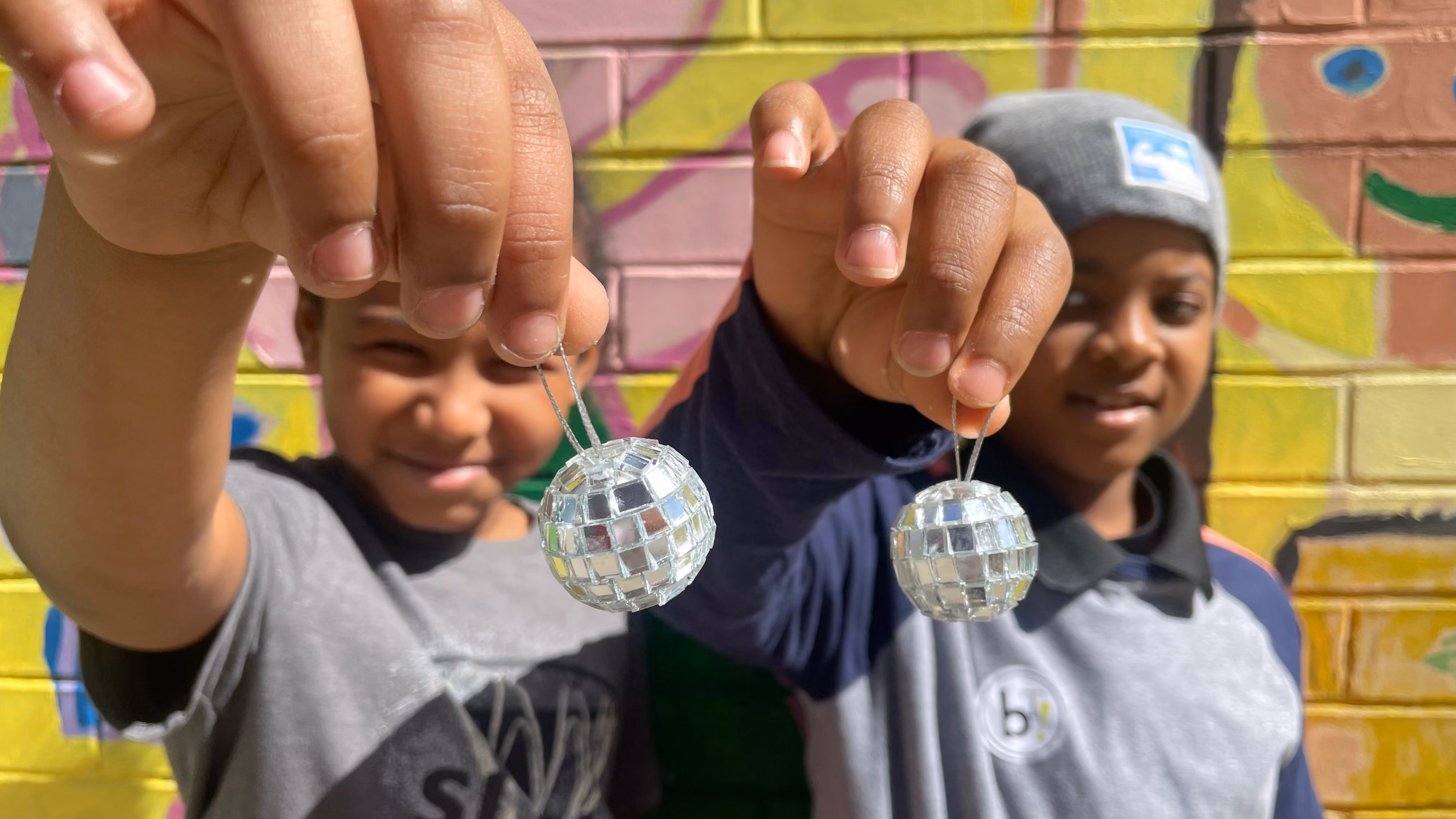 Two students holding handmade mirror ball ornaments