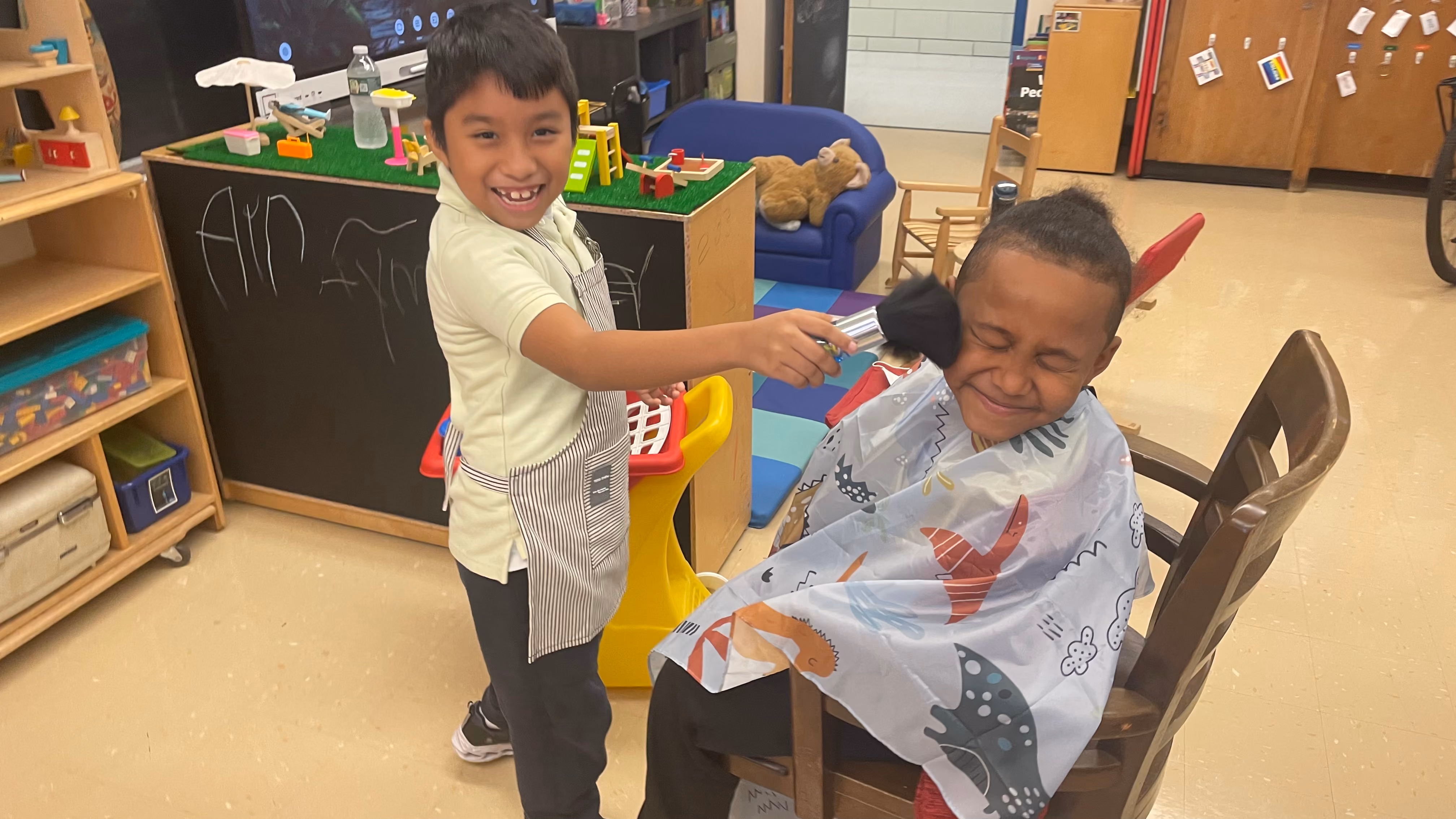 Two students playing pretend barber shop in classroom