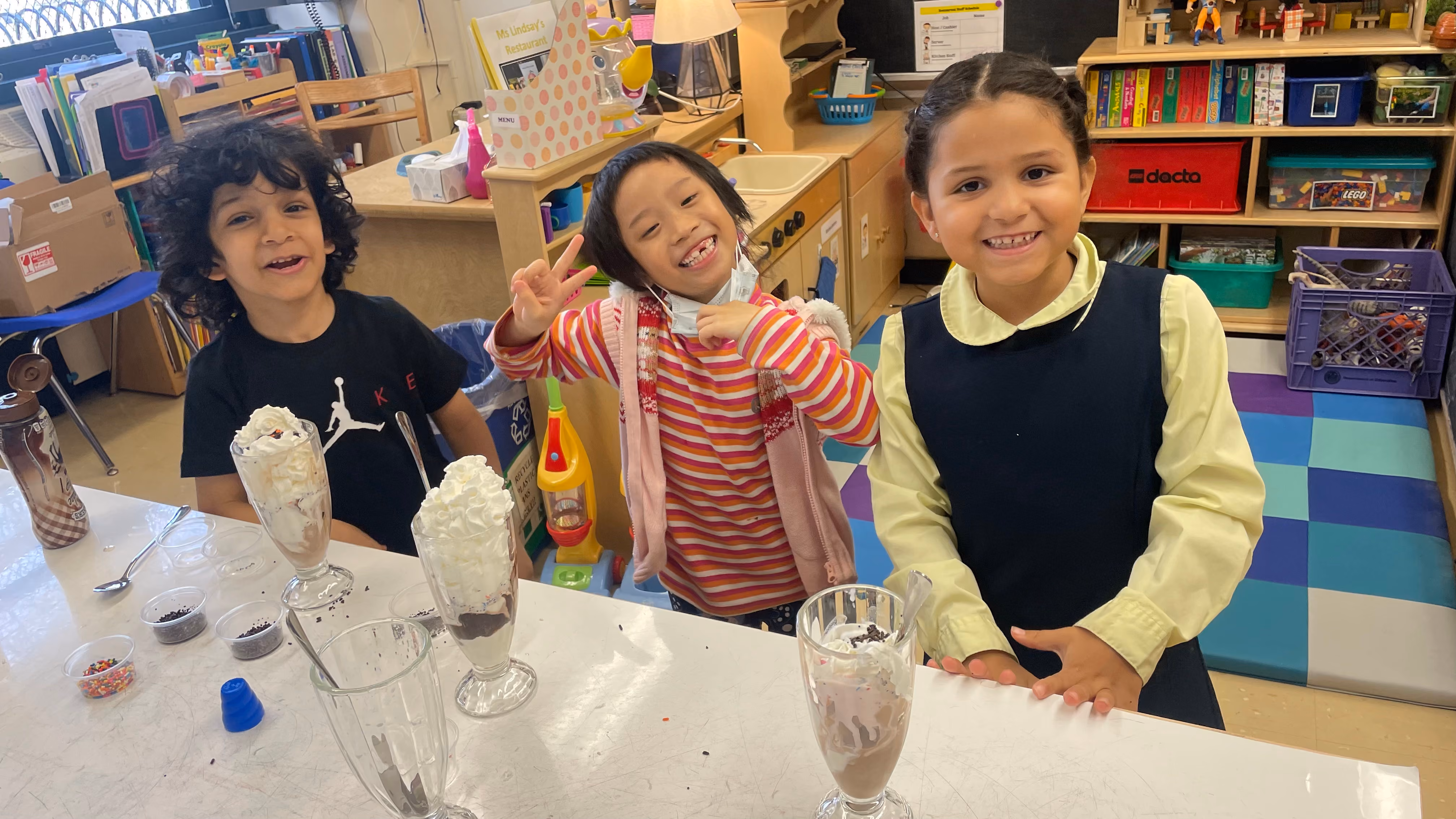 Three students making ice cream sundaes in classroom