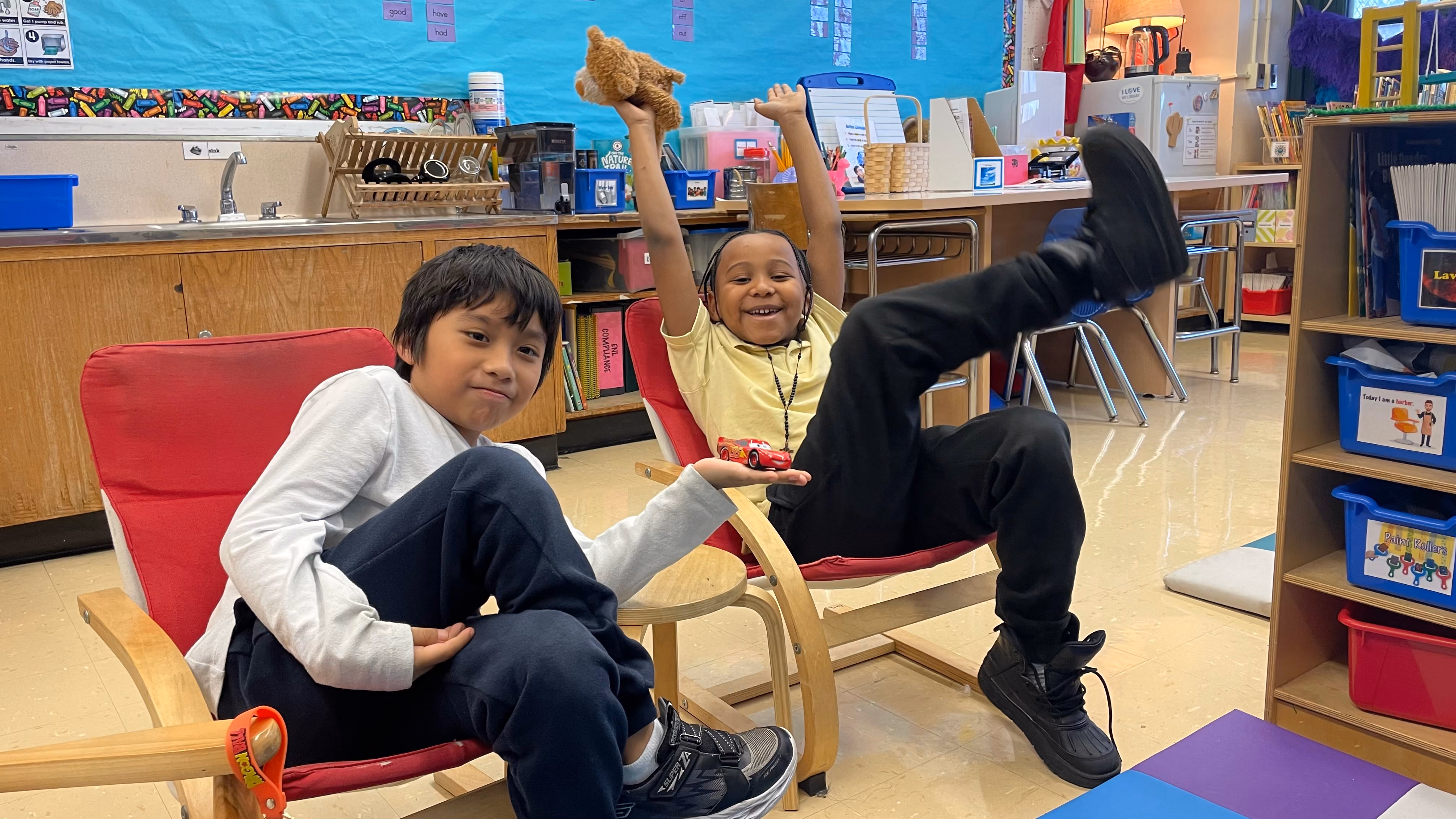 Two students relaxing in red chairs in classroom