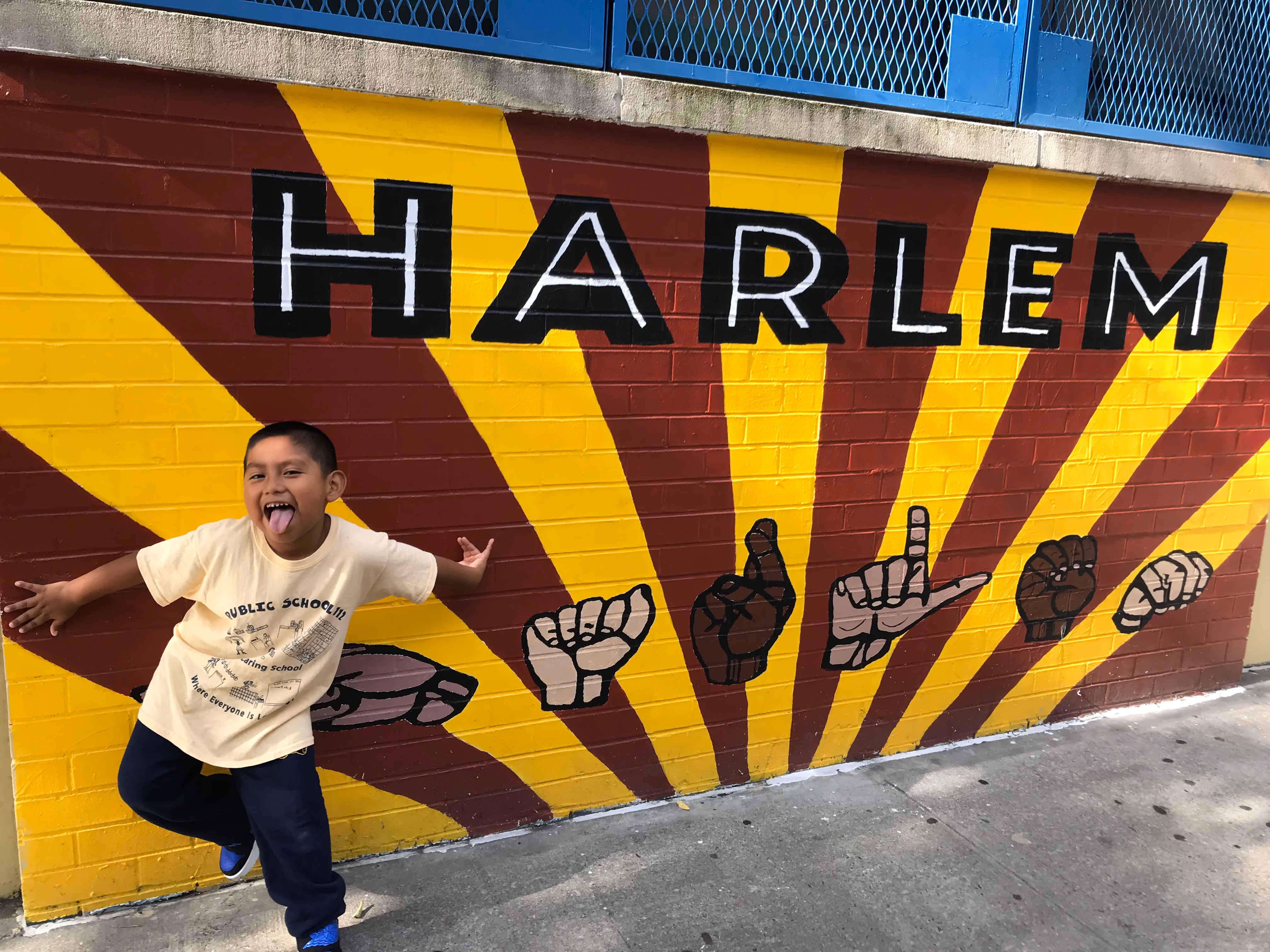 Student posing playfully in front of Harlem mural