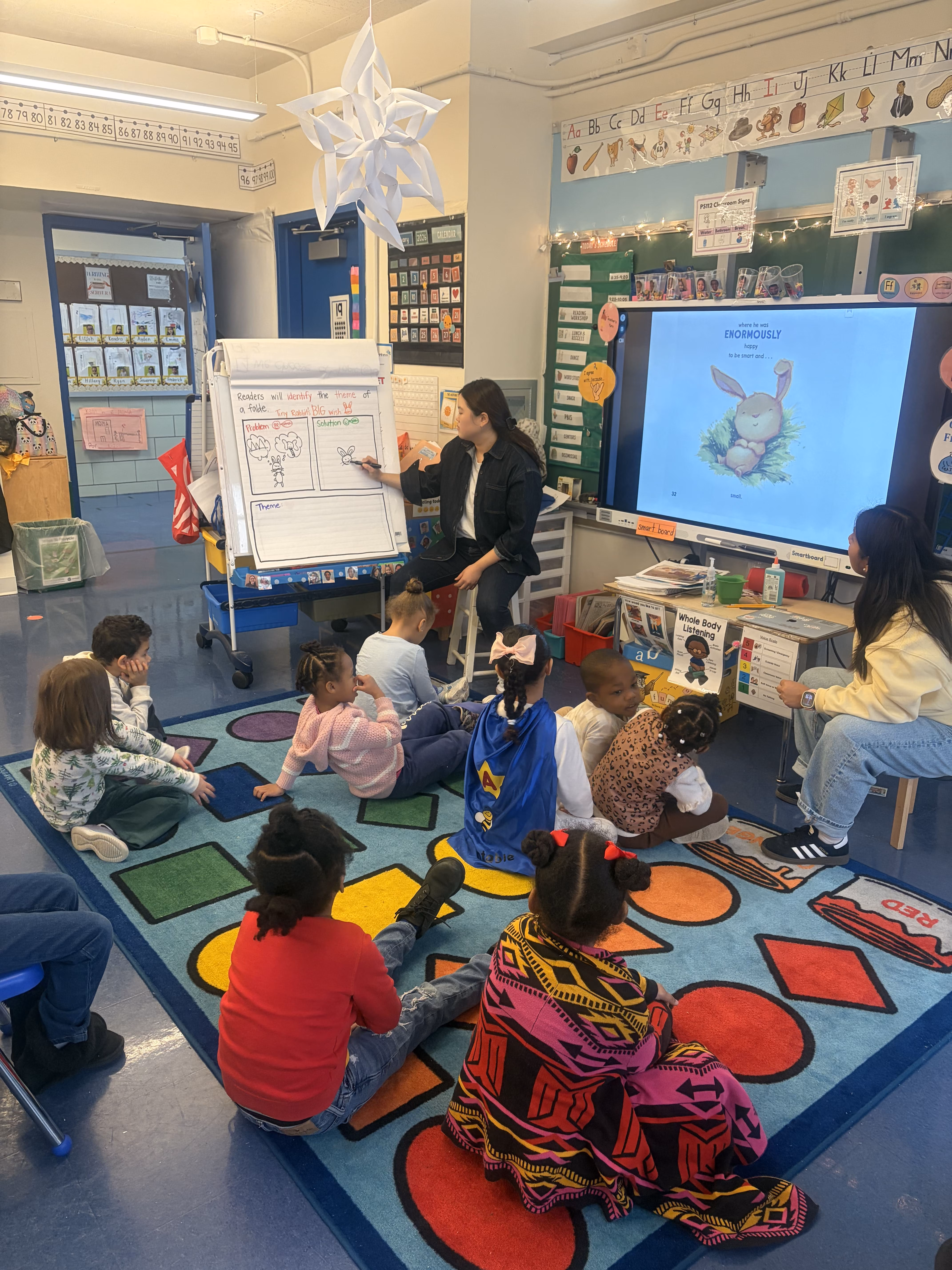 Teacher leading story time lesson for elementary students seated on classroom rug