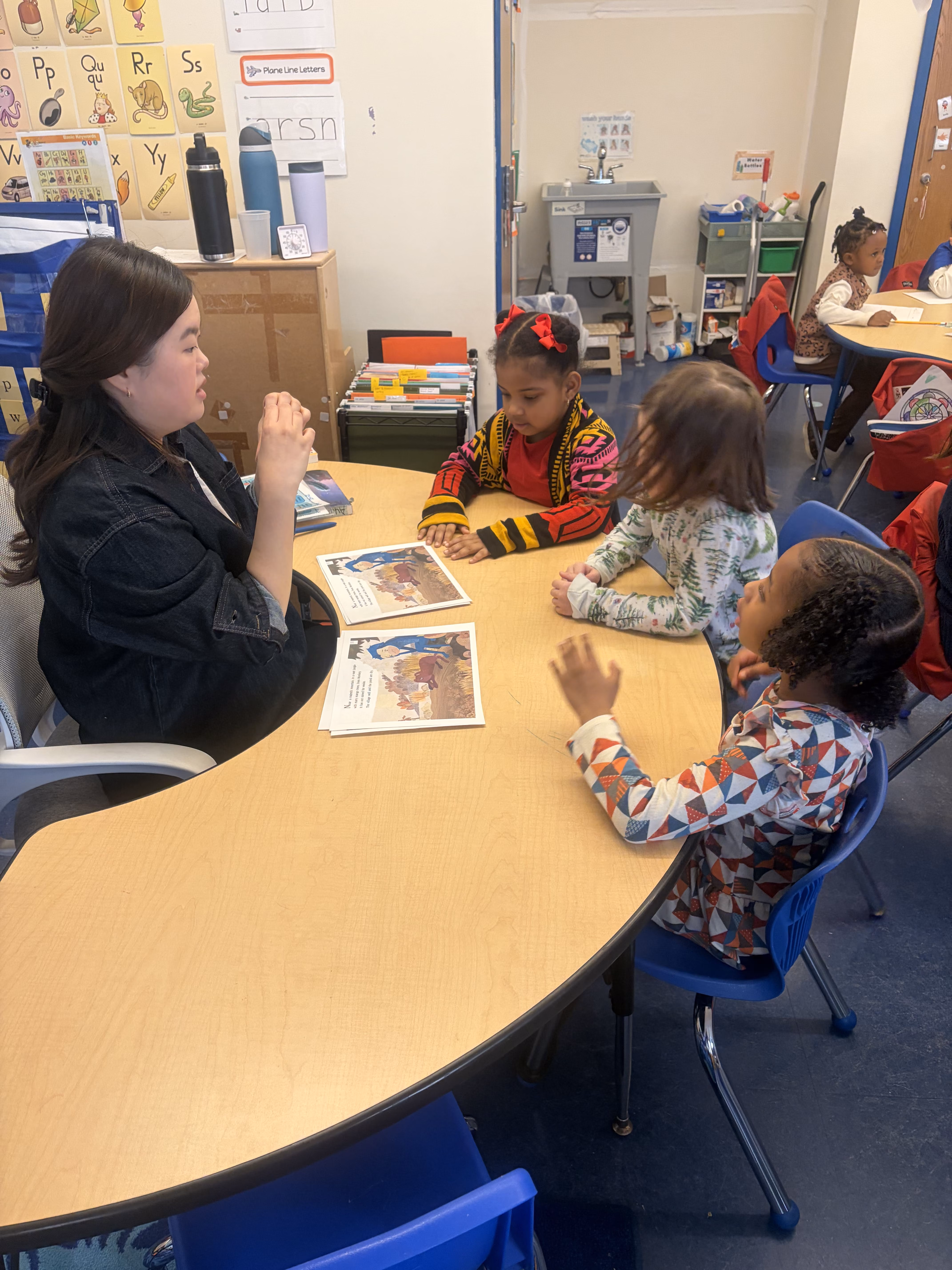 Teacher reading with students at classroom table