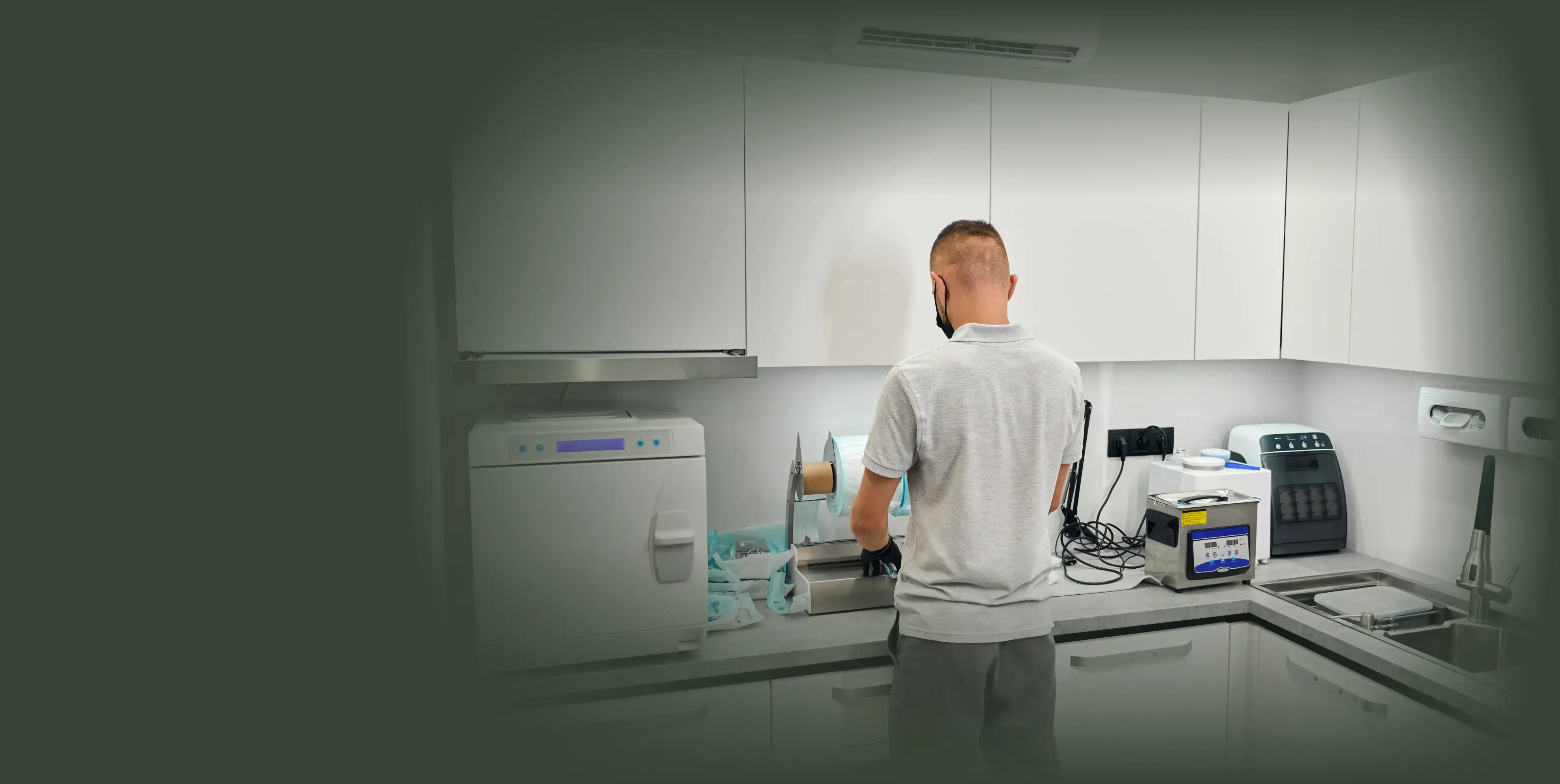 A person wearing a gray shirt is working in a laboratory with various equipment.