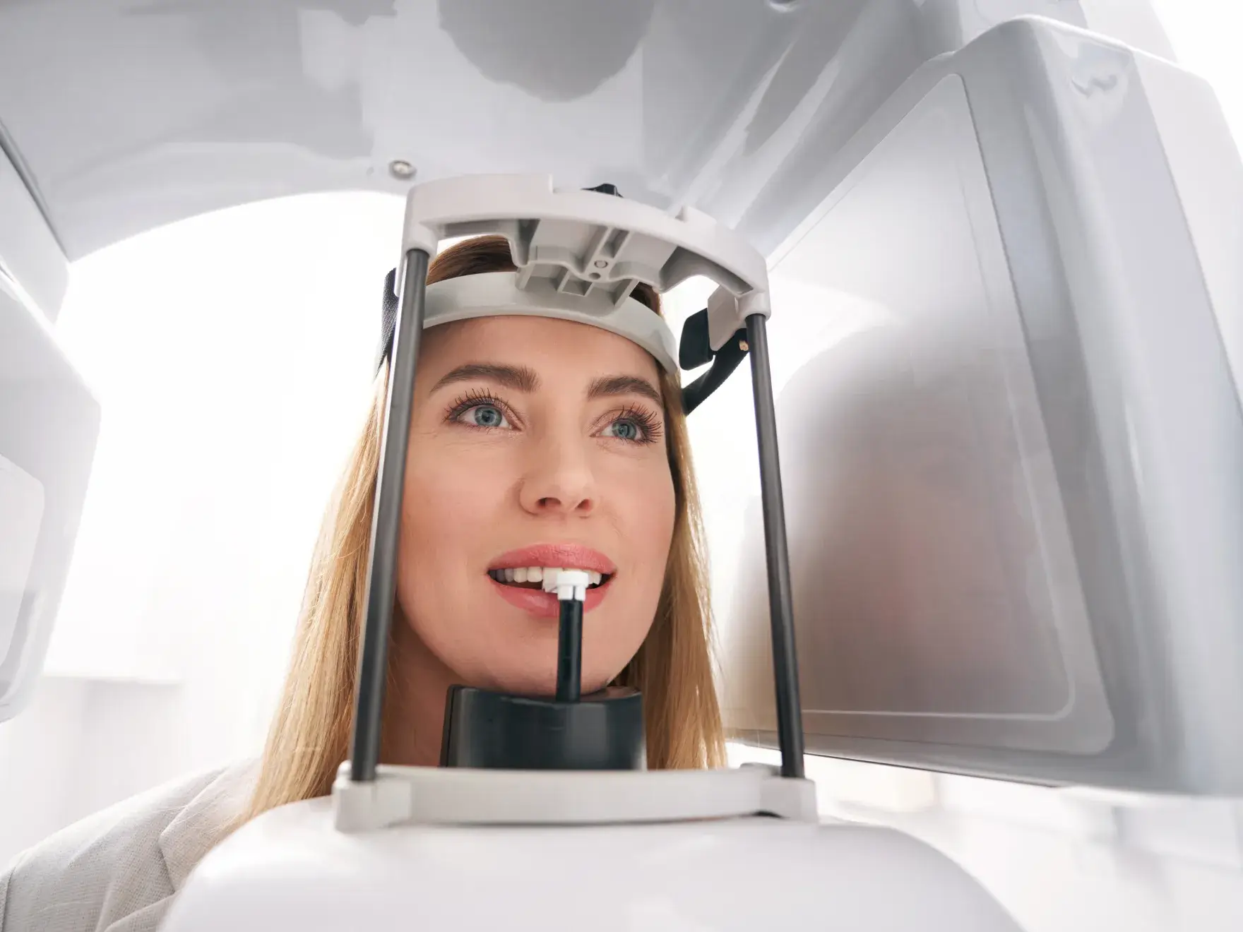 A woman is getting a dental X-ray, biting a tool inside the machine.