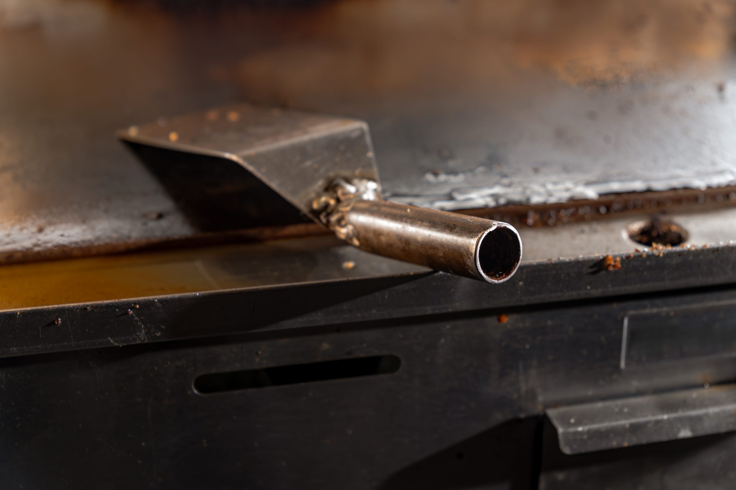 close up of metal spatula on hot griddle in commercial kitchen