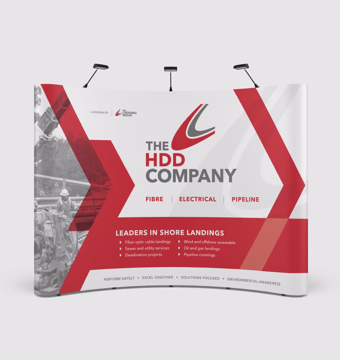 Trade show booth banner for The HDD Company featuring red and gray geometric accents, listing services like fiber optic cable landings and pipeline crossings.