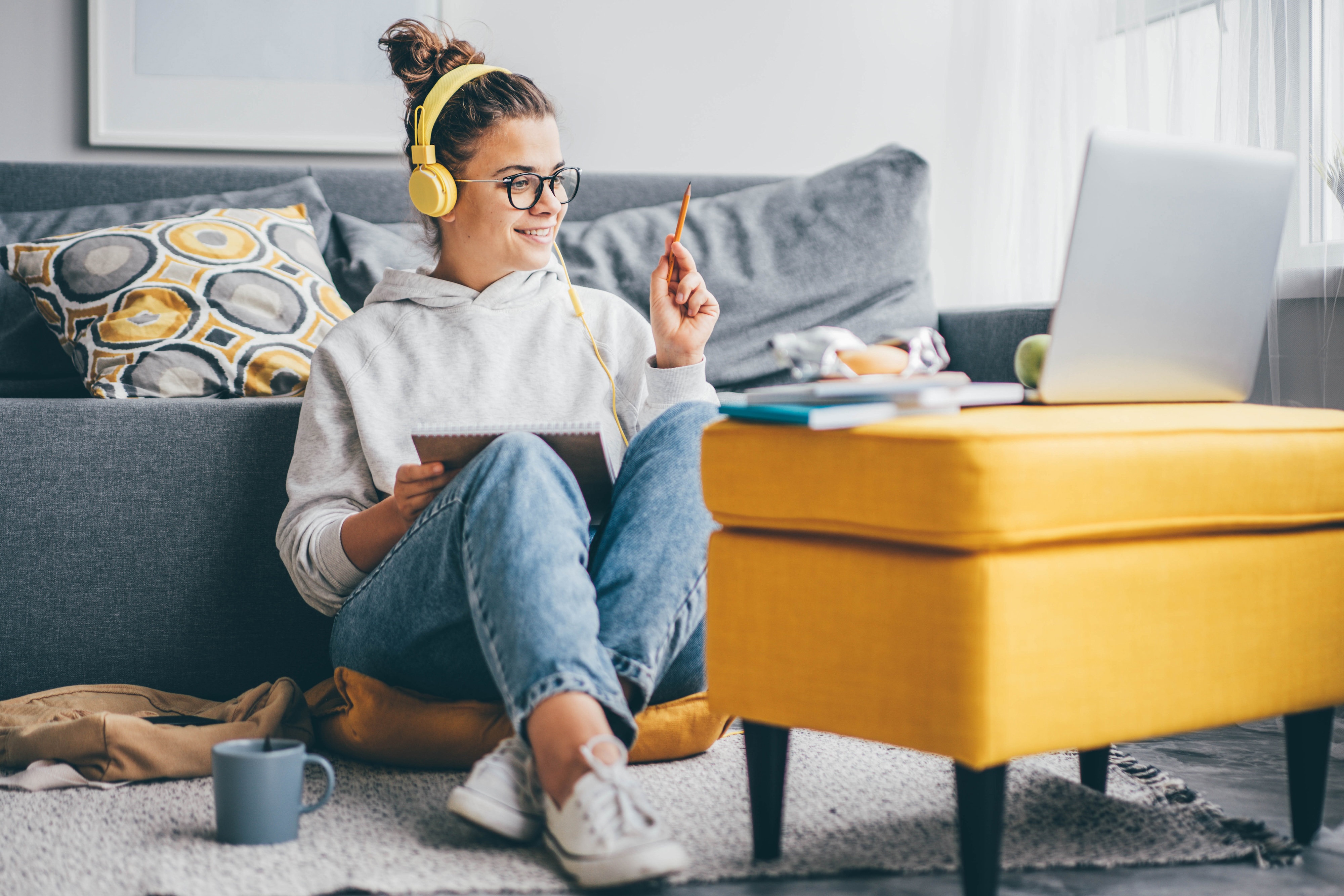 Student on their computer leaning on couch in apartment