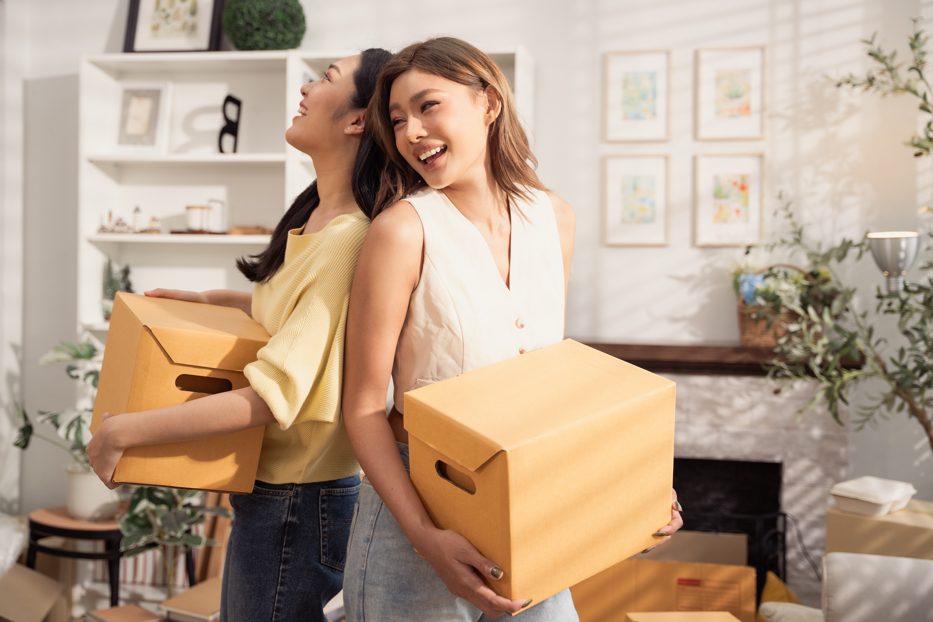 Happy student standing with moving boxes in their apartment