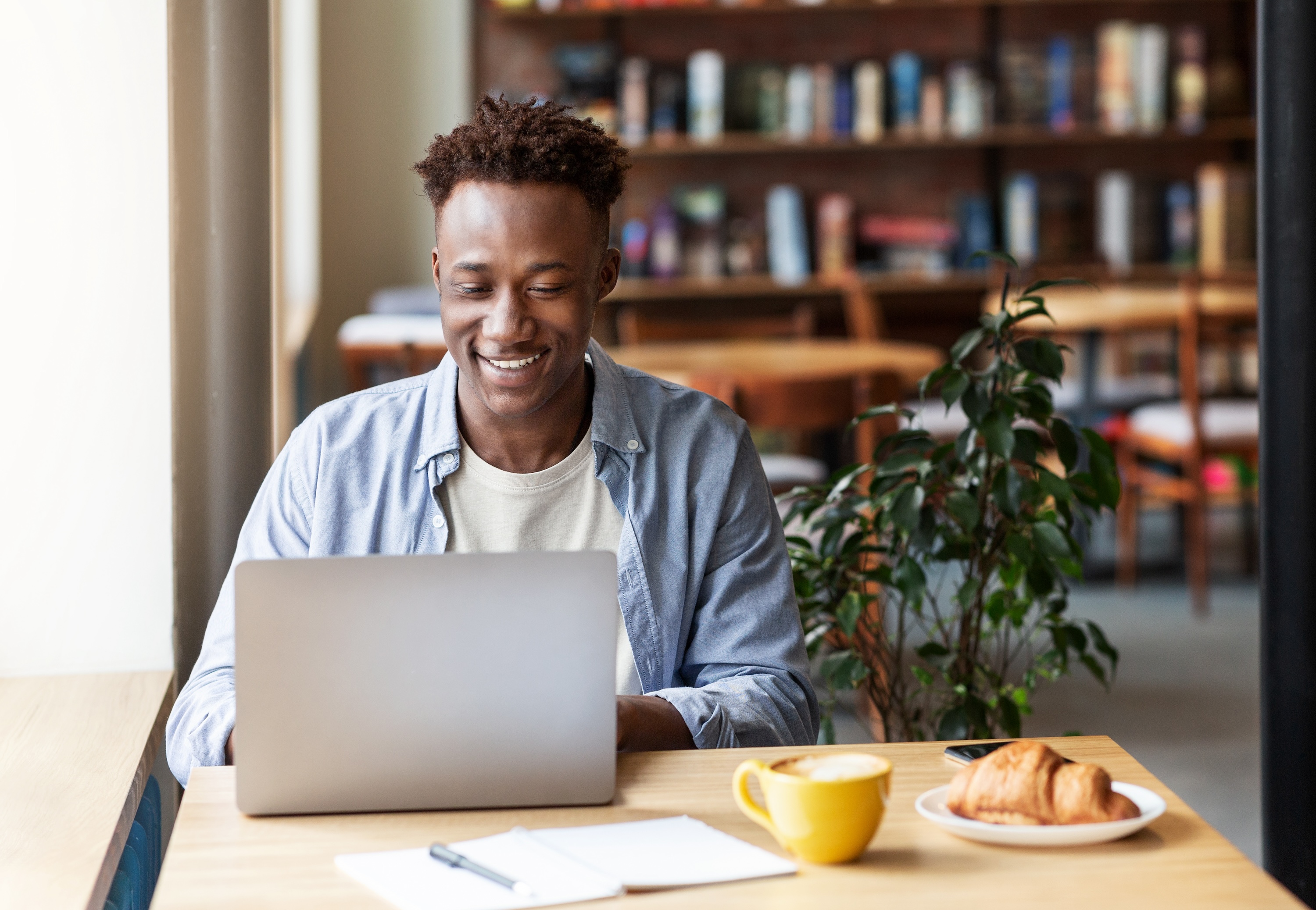 Person working on a laptop with coffee and a croissant near Villa West, Oxford