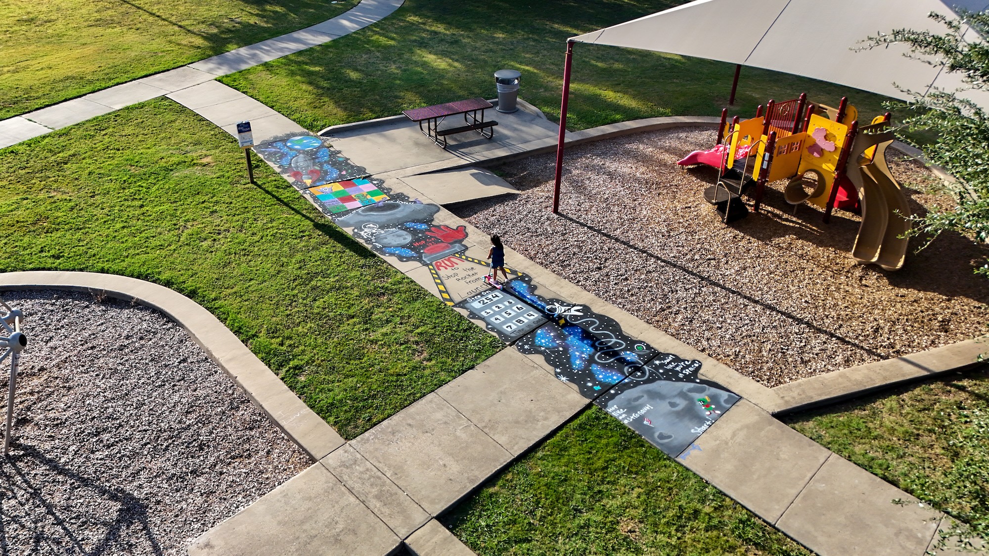Aerial view of a space-themed sidewalk obstacle course beside a playground in South Waco.