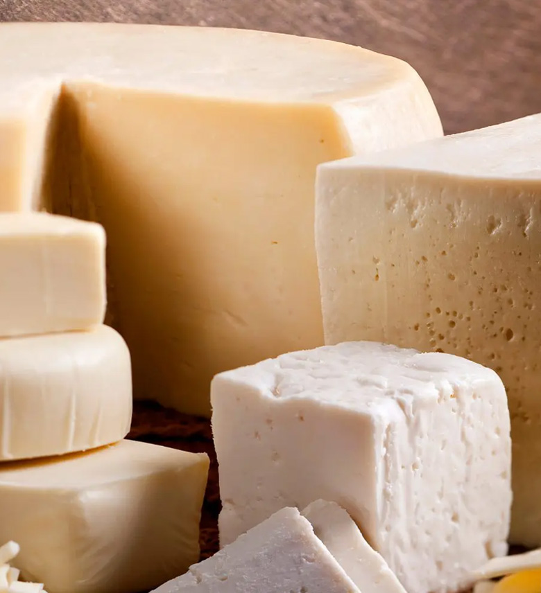 Verschiedene Käsesorten in großen Stücken mit glatter und leicht körniger Textur.